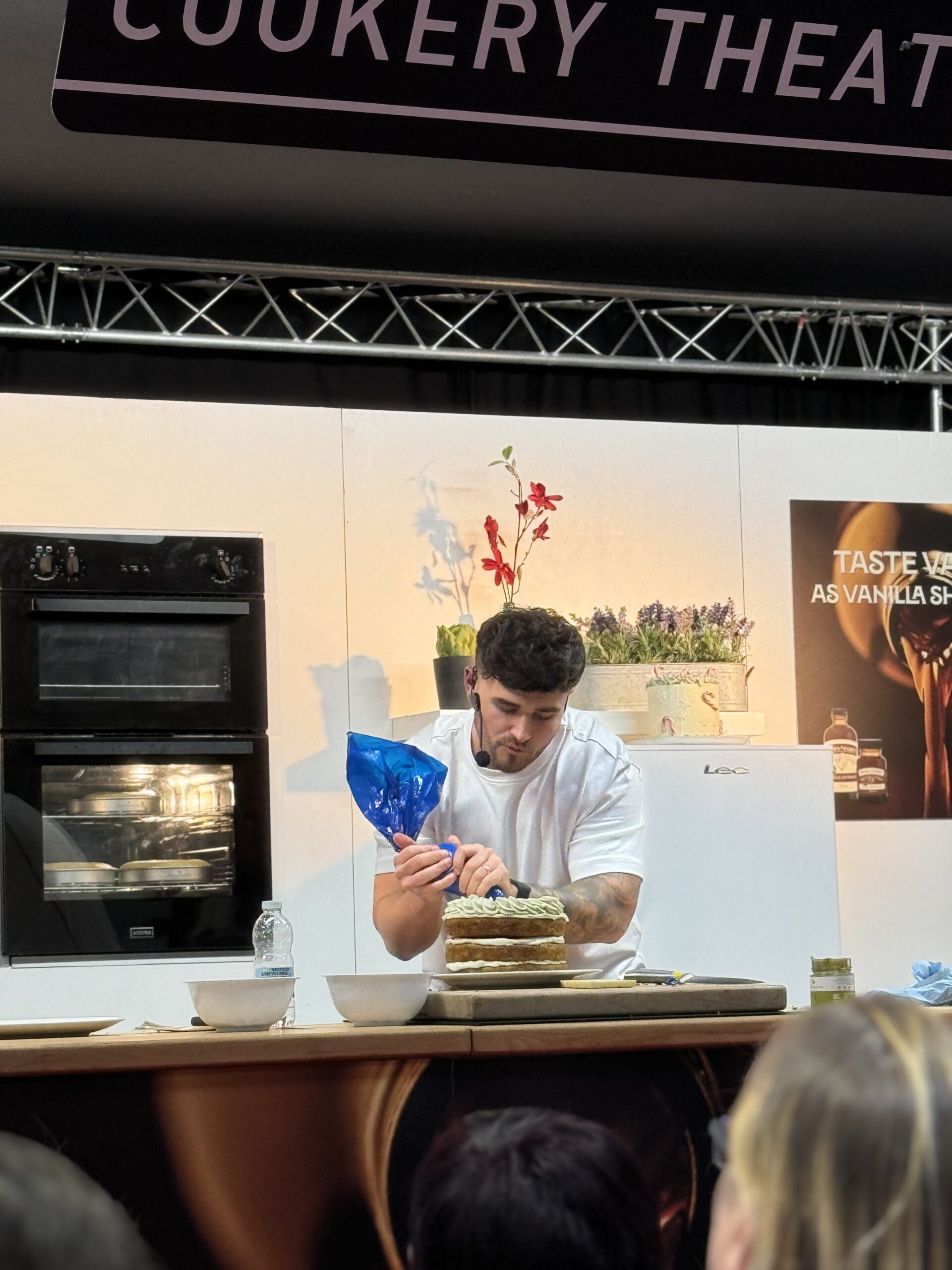 Matty piping onto a cake he has made on stage at a festival